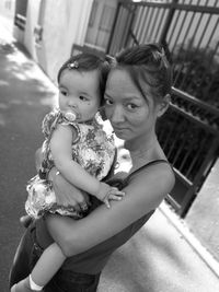 Portrait of woman with daughter standing on street