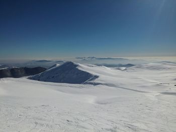 Scenic view of snow covered landscape against clear blue sky