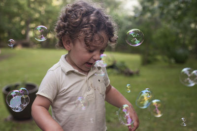 Boy playing with bubbles at park