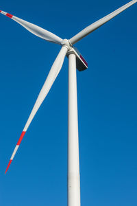 Low angle view of wind turbine against blue sky