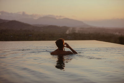 Full length of woman in lake against sky during sunset