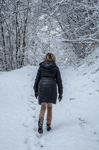 Rear view of woman standing on snow covered field