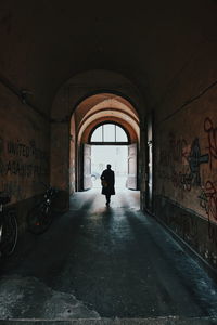 Rear view of person walking in tunnel