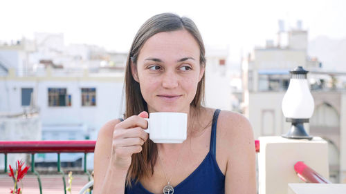 Woman looking away while drinking coffee at cafe
