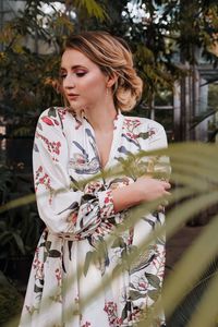 Beautiful young woman standing against plants