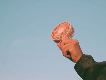 Low angle view of person holding umbrella against clear sky