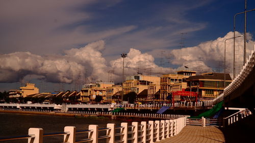 Buildings by river against sky in city