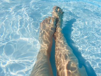 Low section of person relaxing in swimming pool