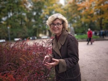 Portrait of smiling woman standing by plants during autumn