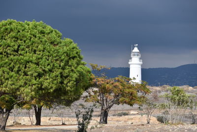 Trees by lighthouse against sky