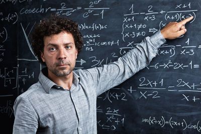 Portrait of teacher pointing on blackboard