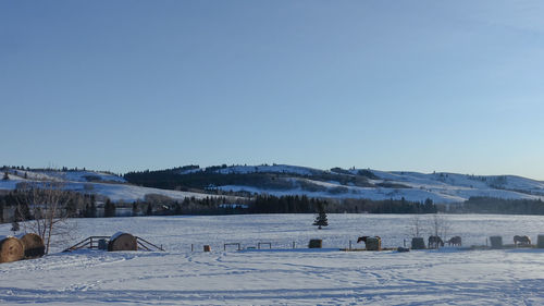 Snow covered landscape against clear blue sky