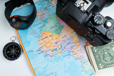 High angle view of map with camera and money on white background