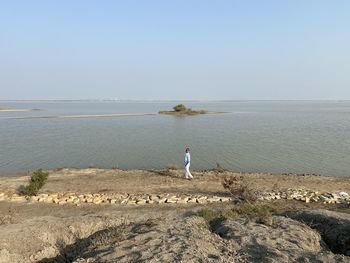 Man on beach against clear sky