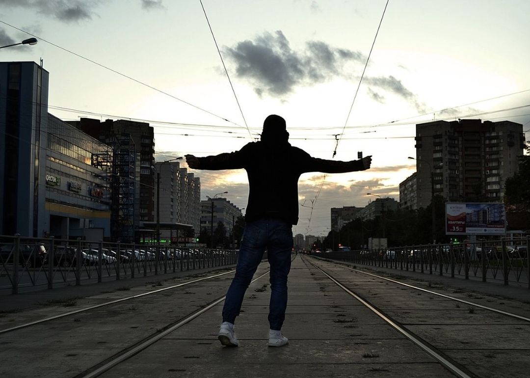 REAR VIEW OF SILHOUETTE MAN STANDING ON RAILROAD TRACK