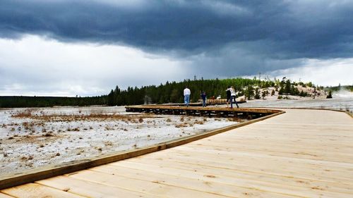 Pier on sea against cloudy sky