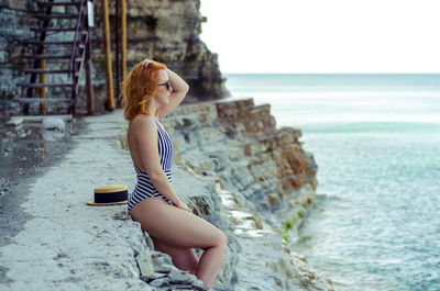 Profile view of woman standing in swimsuit on shore