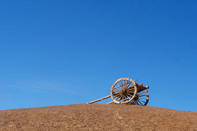 Low angle view of ferris wheel on field against clear blue sky