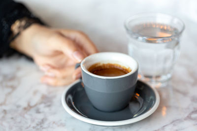 Cropped image of hand holding coffee on table