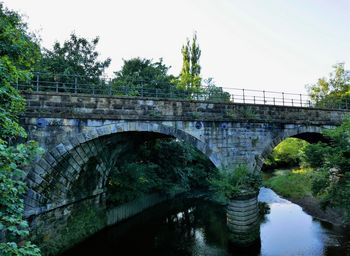 Arch bridge over river against sky