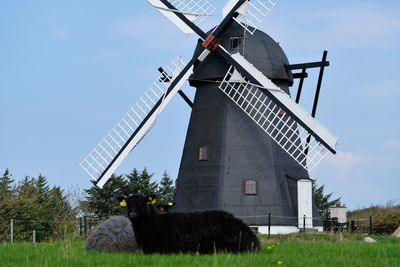 Traditional windmill on field against sky