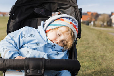 Close-up of girl sleeping in baby stroller on field