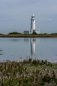 Lighthouse by sea against sky