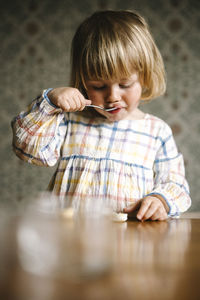 Blond girl with bangs eating food at table