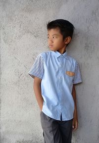 Portrait of boy standing against wall