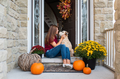 Rear view of woman with dog sitting by entrance