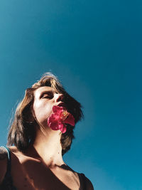 Low angle view of woman looking away against blue wall