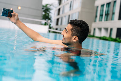 Young man making a selfie inside a pool