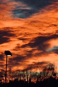 Low angle view of silhouette trees against dramatic sky