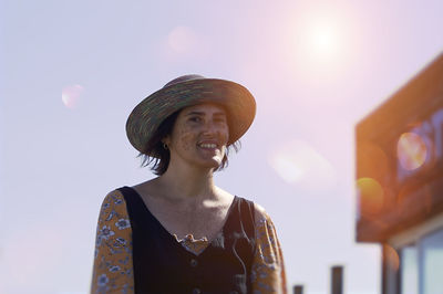Portrait of young woman wearing hat against sky