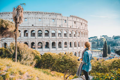 Woman standing by coliseum against sky