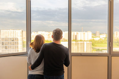 Man hugging his wife. young couple moving in new apartmen. people looks out window at new 