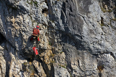 Aerial view of mountain rescuer abseiling on a rocky wall hanging on a rope