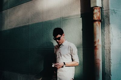 Young man looking at camera while standing against wall