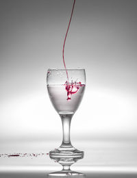 Close-up of wineglass on glass against white background