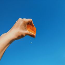 Low angle view of person hand against clear blue sky