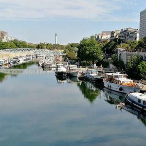 Boats moored at harbor against sky in city