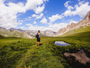 Rear view of man standing on mountain against sky