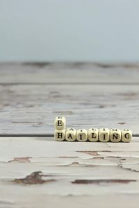 Close-up of text on table at beach against sky
