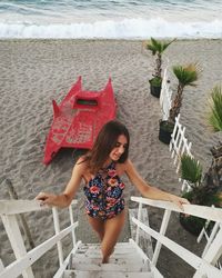 High angle view of young woman moving up on ladder at beach