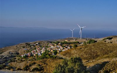 Windmills by sea against sky
