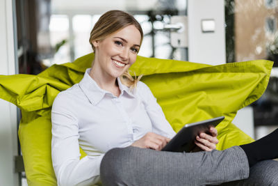 Portrait of smiling young woman sitting on sofa