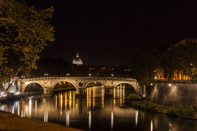 Arch bridge over river against clear sky at night