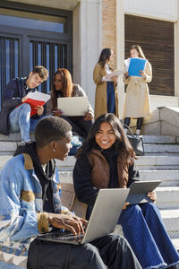 Multiracial college students studying on steps on campus