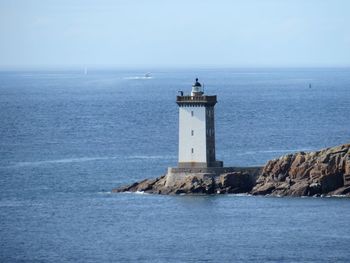 Lighthouse by sea against sky