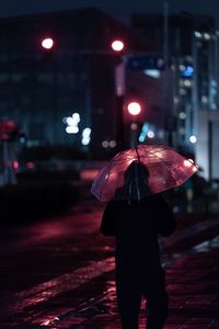 Rear view of man on wet street at night